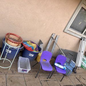 Assorted items, including chairs, buckets, and a window, against a stucco wall.