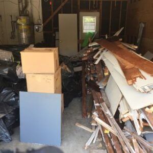 A cluttered garage with boxes, debris, and a door.