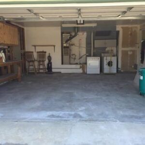 Empty garage with concrete floor, laundry appliances, and workbenches.