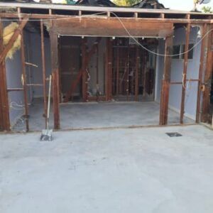 Construction site, room partially demolished. Concrete floor, exposed wooden frame, debris.