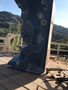 A dark blue hot tub on a wooden deck with a mountain background.
