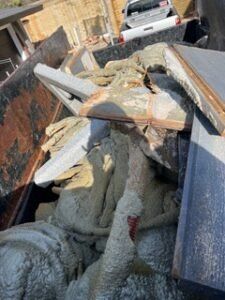 Dumpster filled with concrete and debris; a truck is visible in the background.