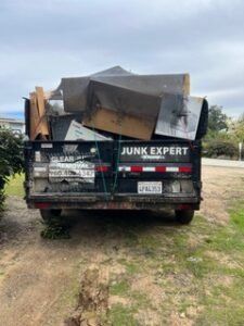 Black truck filled with junk, parked outdoors. 