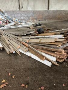 Pile of weathered wooden planks in a gray indoor setting, likely construction debris.