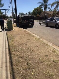 Street scene: garbage truck parked, person walking on sidewalk, car, trailer.