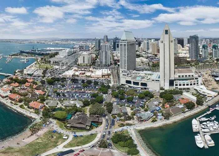 San Diego, California waterfront with city skyline, harbor, and ships. Blue water, buildings, sunny.
