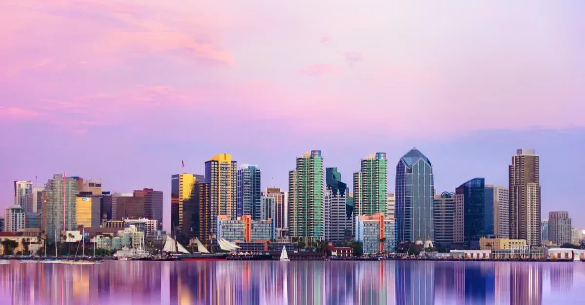 Downtown San Diego skyline at sunset, with buildings reflecting in purple water.