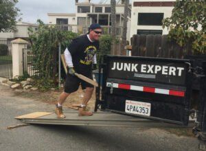 Man pushing debris onto a truck labeled 
