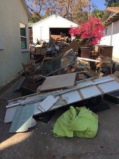 Pile of discarded household items, including furniture and construction debris, sits outside.