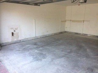 Empty garage interior with concrete floor and off-white walls.