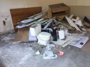 Pile of construction debris and a toilet in a garage.