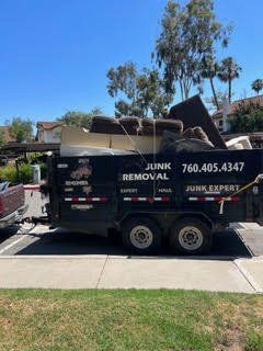 Black trailer filled with junk; phone number for junk removal on side.