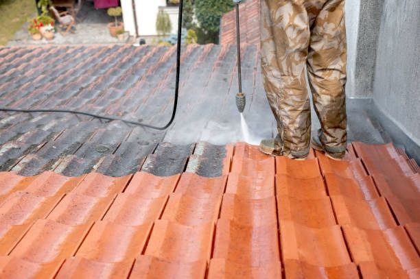 A man is cleaning the roof of a house with a soft pressure washer in Coventry.