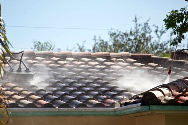 A person is cleaning a tiled roof with a soft pressure washer in Coventry.