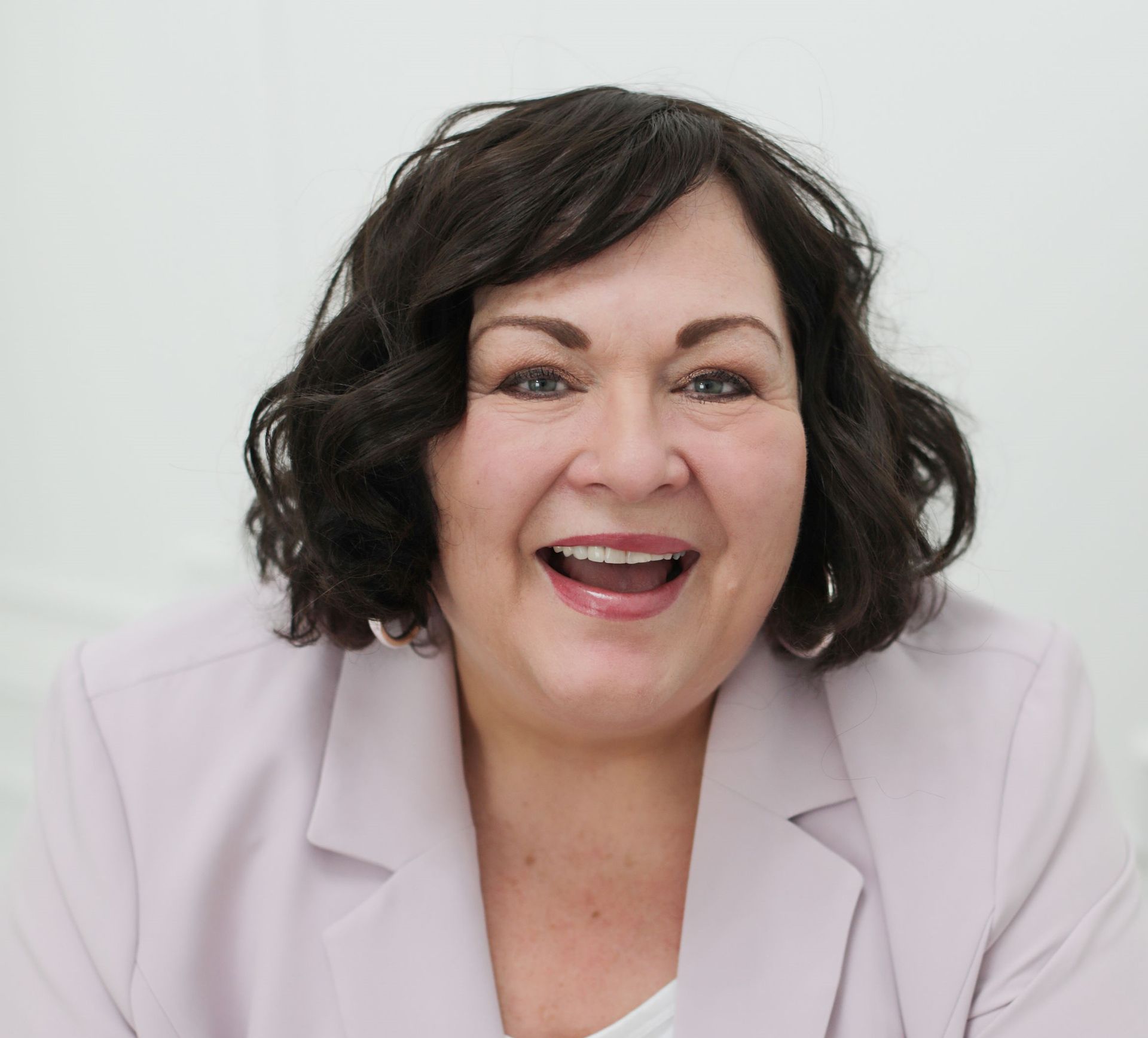 Two men smiling, arm in arm, against a white backdrop. One in a dark blue shirt, the other in a light blue shirt and glasses.