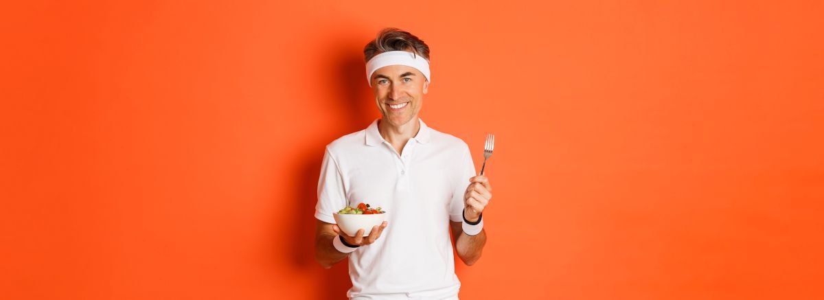 A man is holding a bowl of food and a fork.