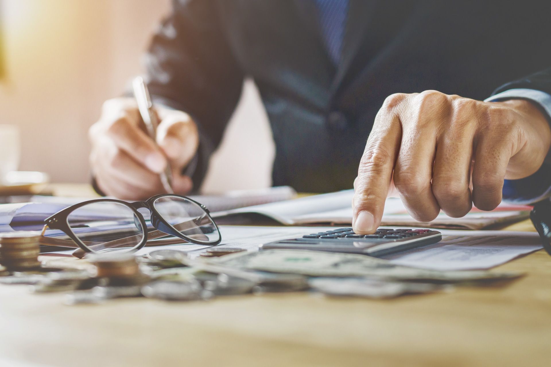 A man is sitting at a table using a calculator and a pen.