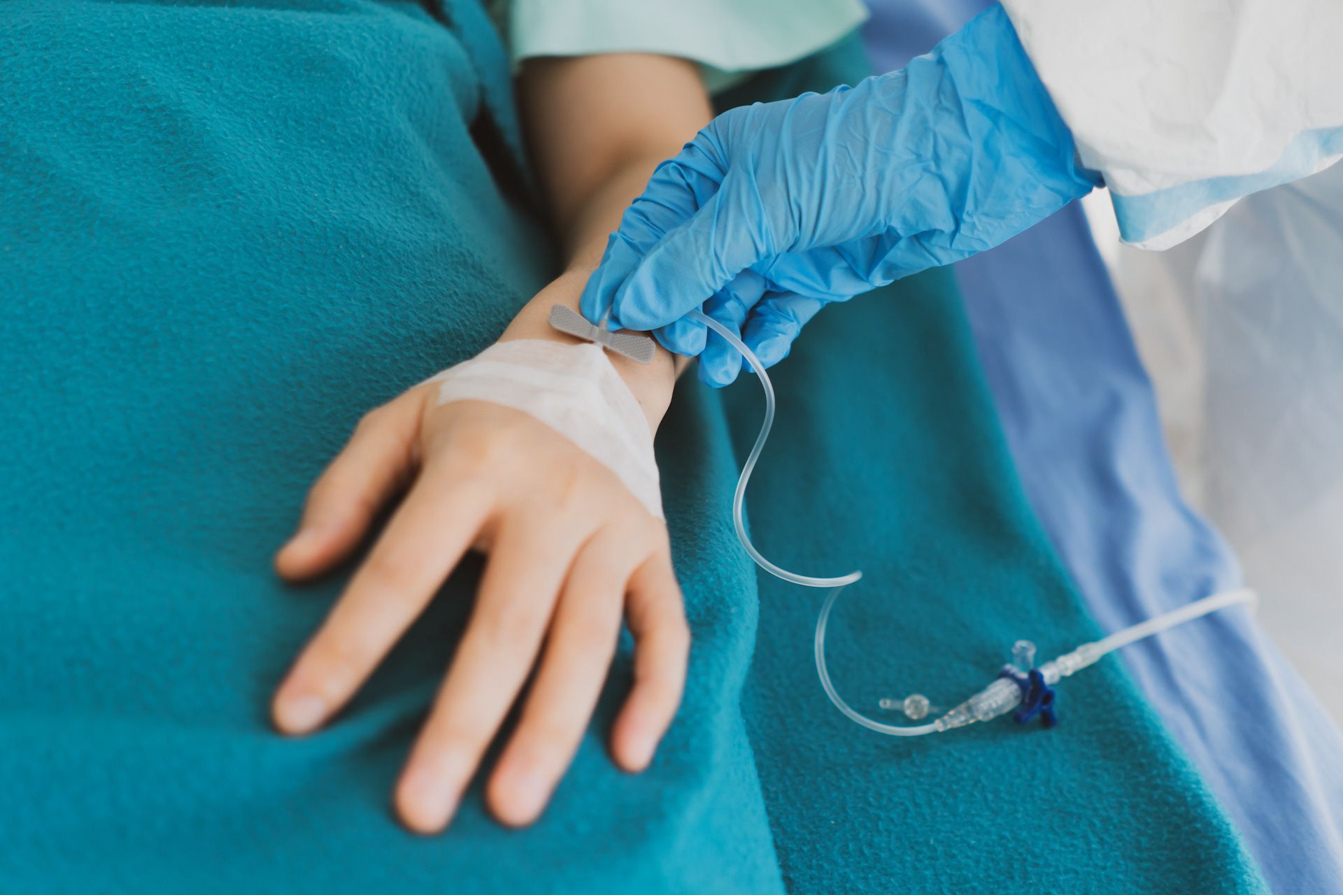 A person is laying in a hospital bed with an iv in their hand.