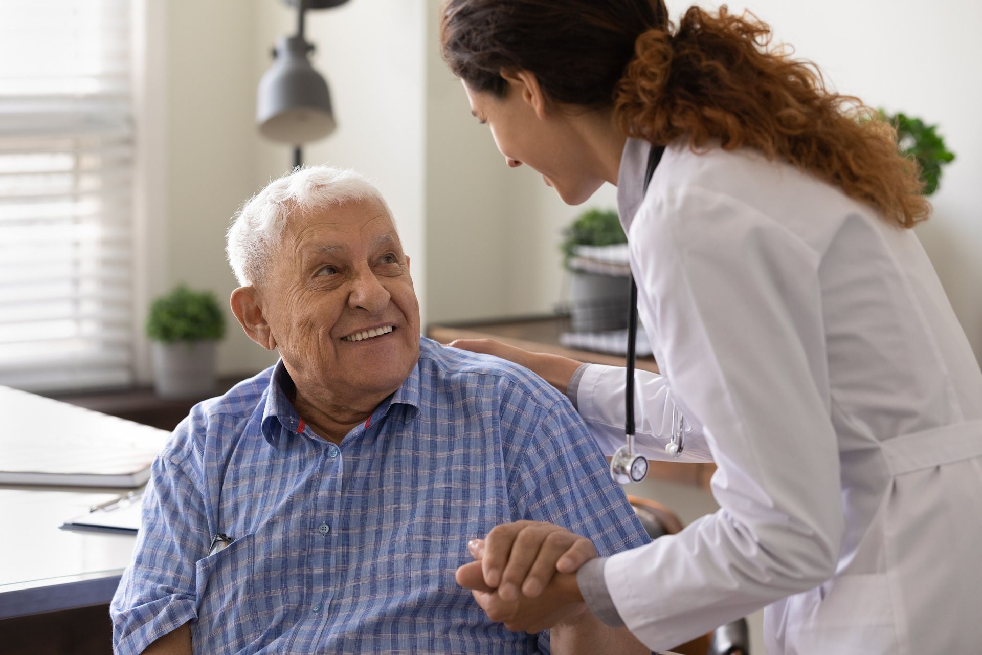 A doctor is holding the hand of an elderly man in a hospital.