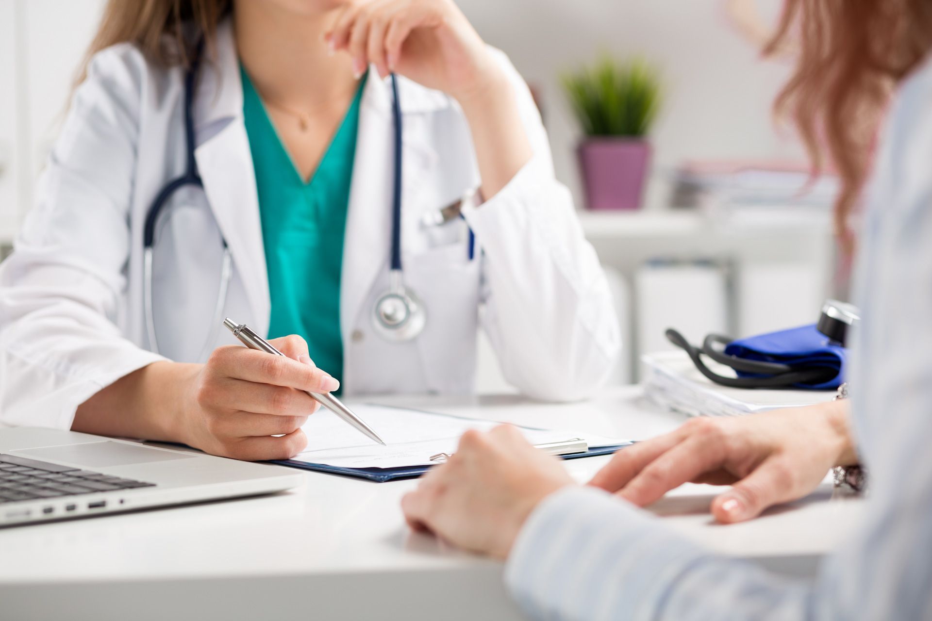 A doctor is sitting at a desk talking to a patient.