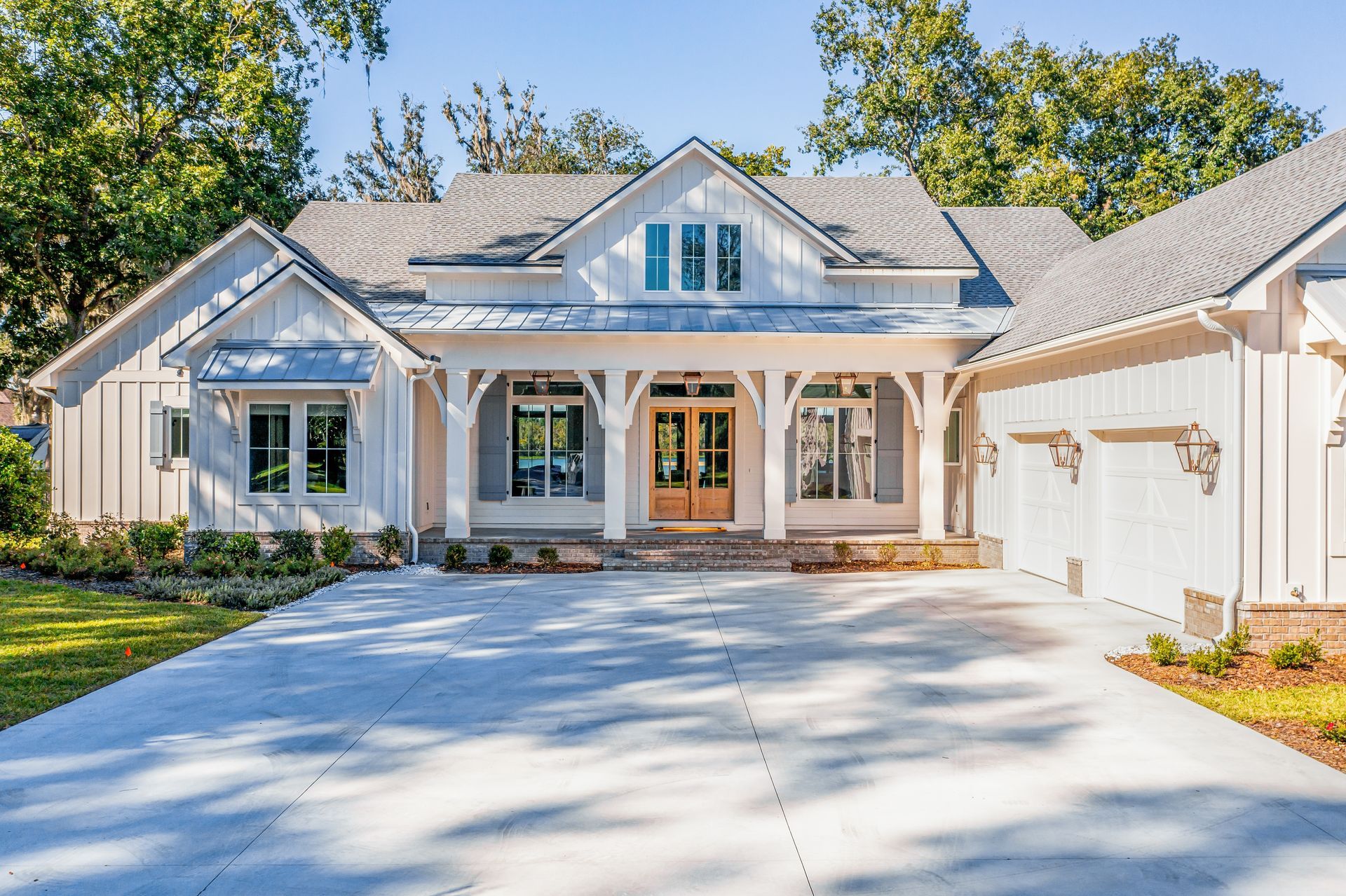 An aerial view of a white house with a blue roof and a driveway.