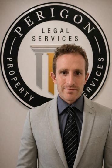 Man in gray suit standing before Perrigon Legal Services sign