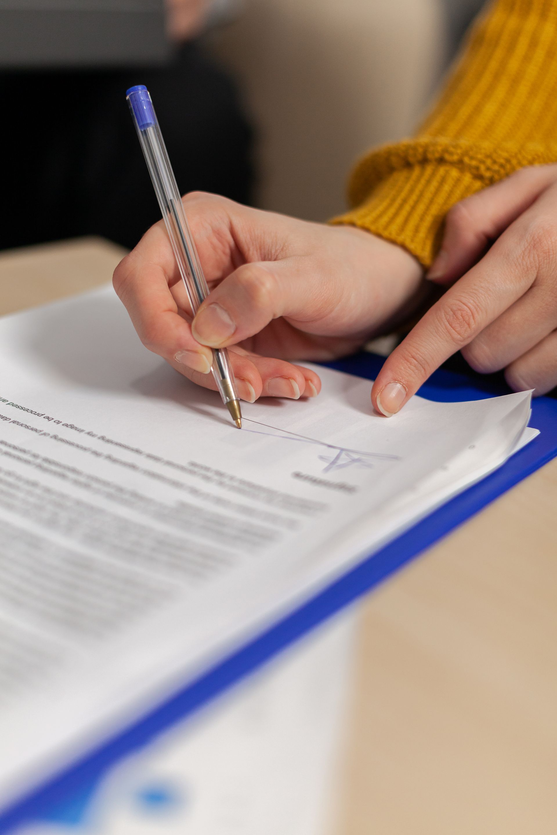 Older man with beard signing document, woman smiles beside him at a table.
