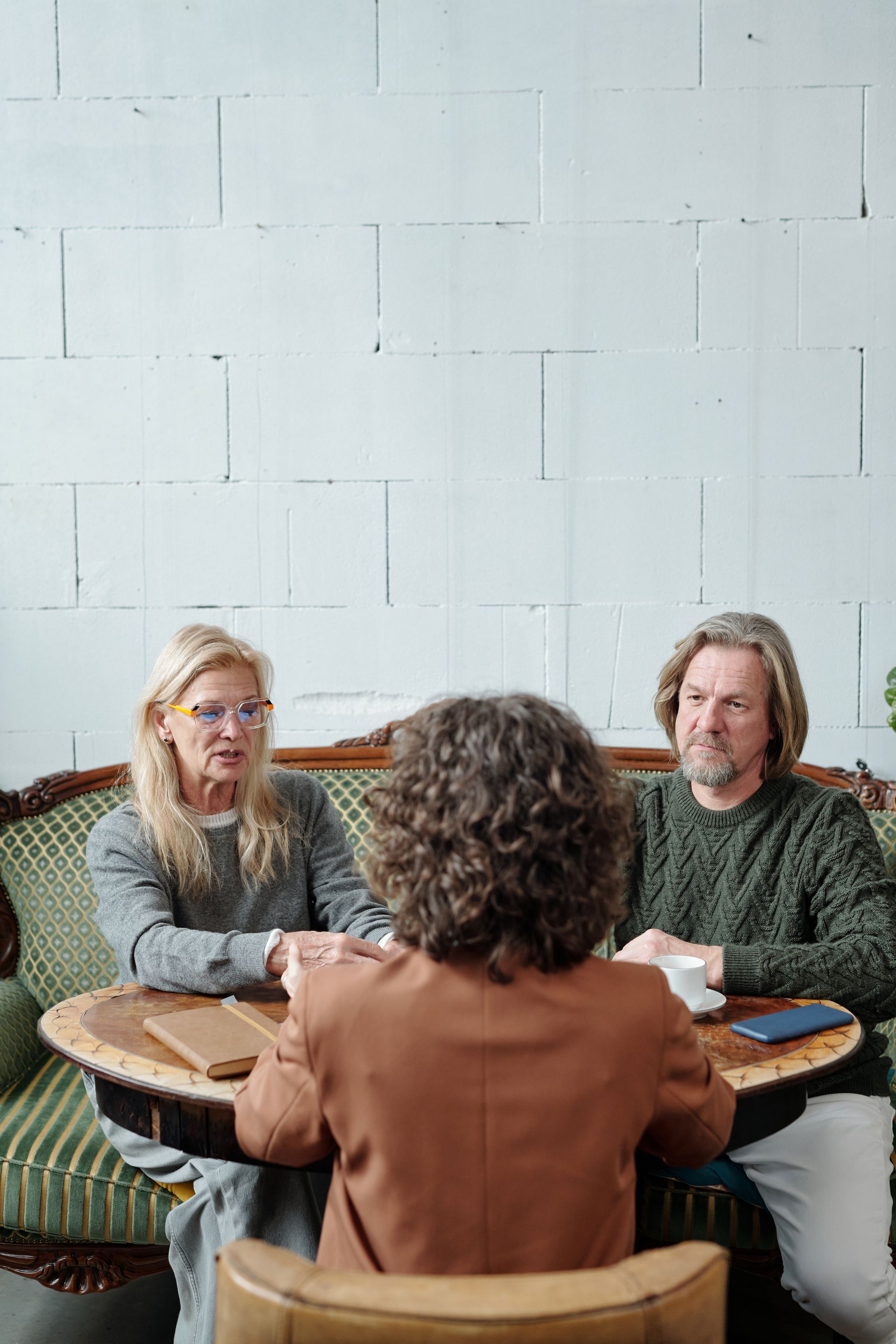 Older man with beard signing document, woman smiles beside him at a table.