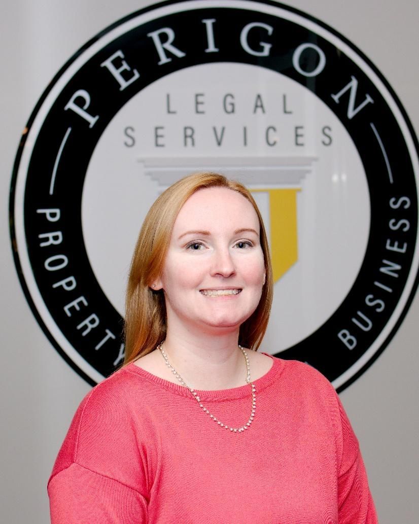 Woman in a pink sweater standing in front of a Perrigon Legal Services sign.