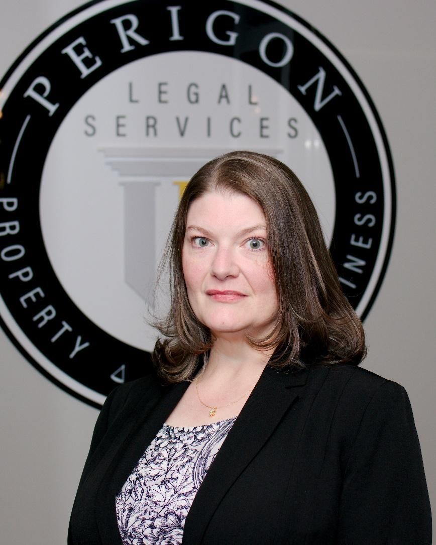 Portrait of a woman in a black blazer before a “Perrigon Legal Services” sign