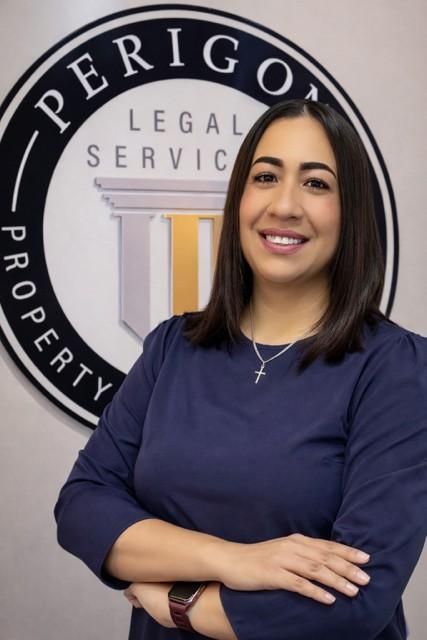 Woman smiling with arms crossed in front of a Perigo Legal Services sign
