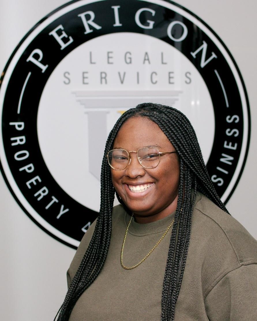 Smiling woman in glasses standing before an OPERIGIN Legal Services logo wall