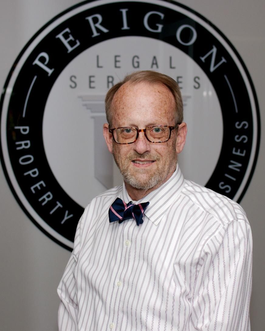 Man in striped shirt and bow tie posing before a legal services logo wall
