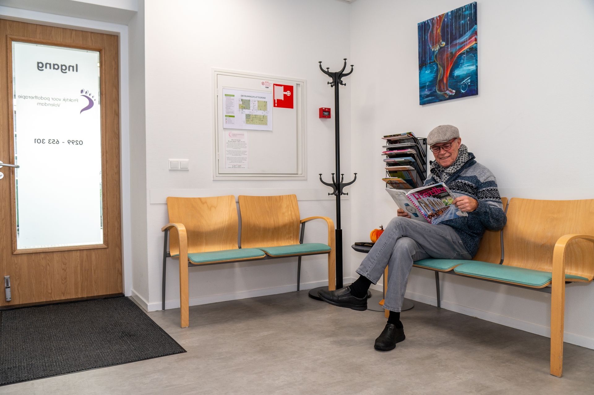 Wachtkamer van Praktijk voor Podotherapie Volendam met patiƫnt die leest terwijl hij wacht op de afspraak.