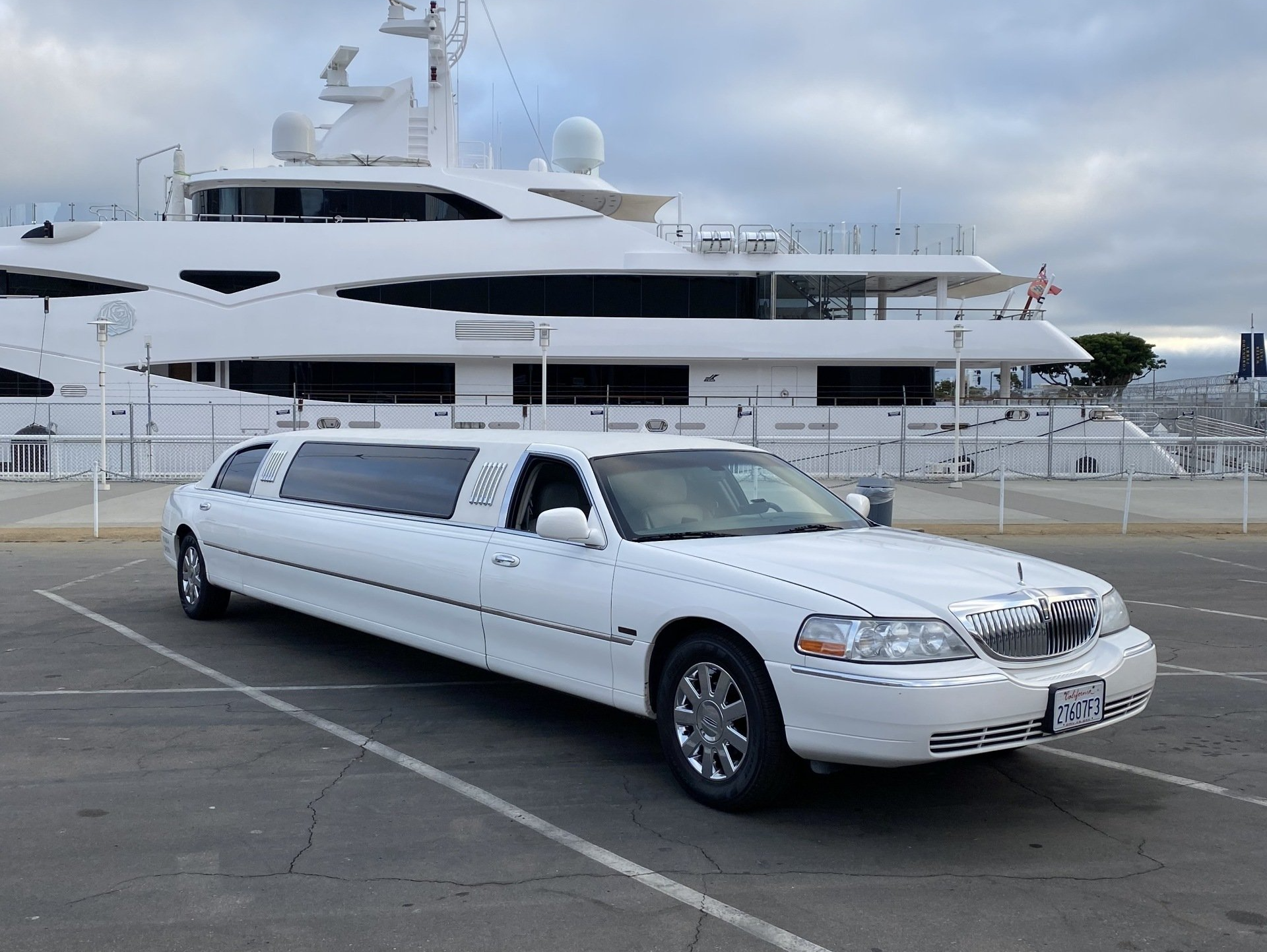 a white limousine is parked in front of a large white yacht .
