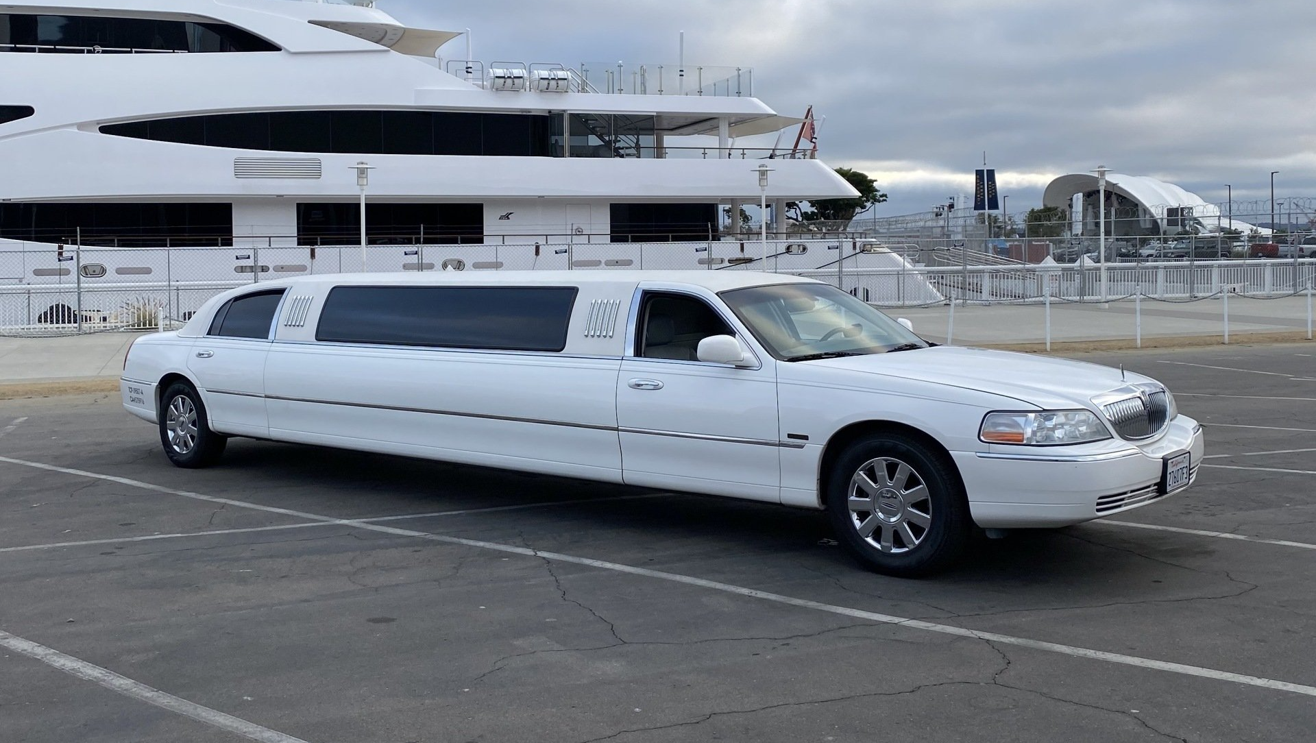 a white limousine is parked in front of a large white boat .