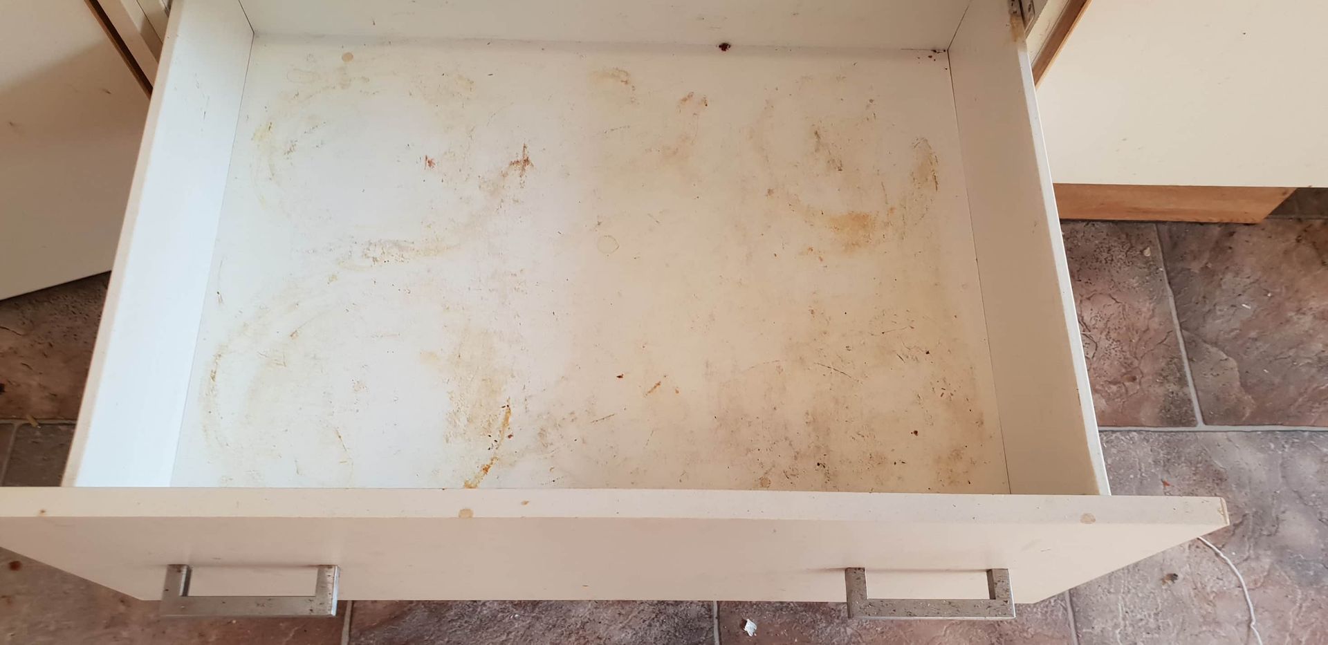 A Dirty Drawer is Sitting on a Tiled Floor in a Kitchen — Lease Clean Newcastle in Newcastle, NSW