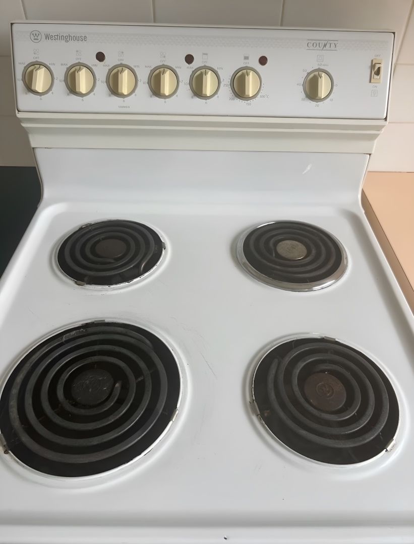 A White Stove Top With Four Black Burners — Lease Clean Newcastle in Newcastle, NSW