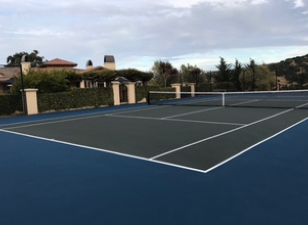 A tennis court with a house in the background