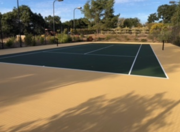 A tennis court with a shadow of a tree on the ground