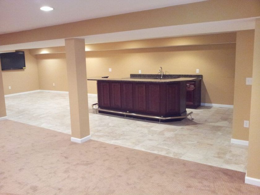 An empty basement with a bar and a flat screen tv