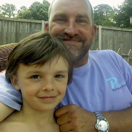 A man wearing a watch is hugging a little boy