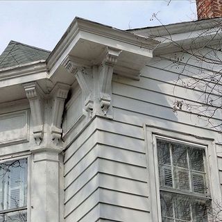 A white house with a roof and a few windows