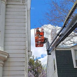 A man is working on the side of a building on a crane.