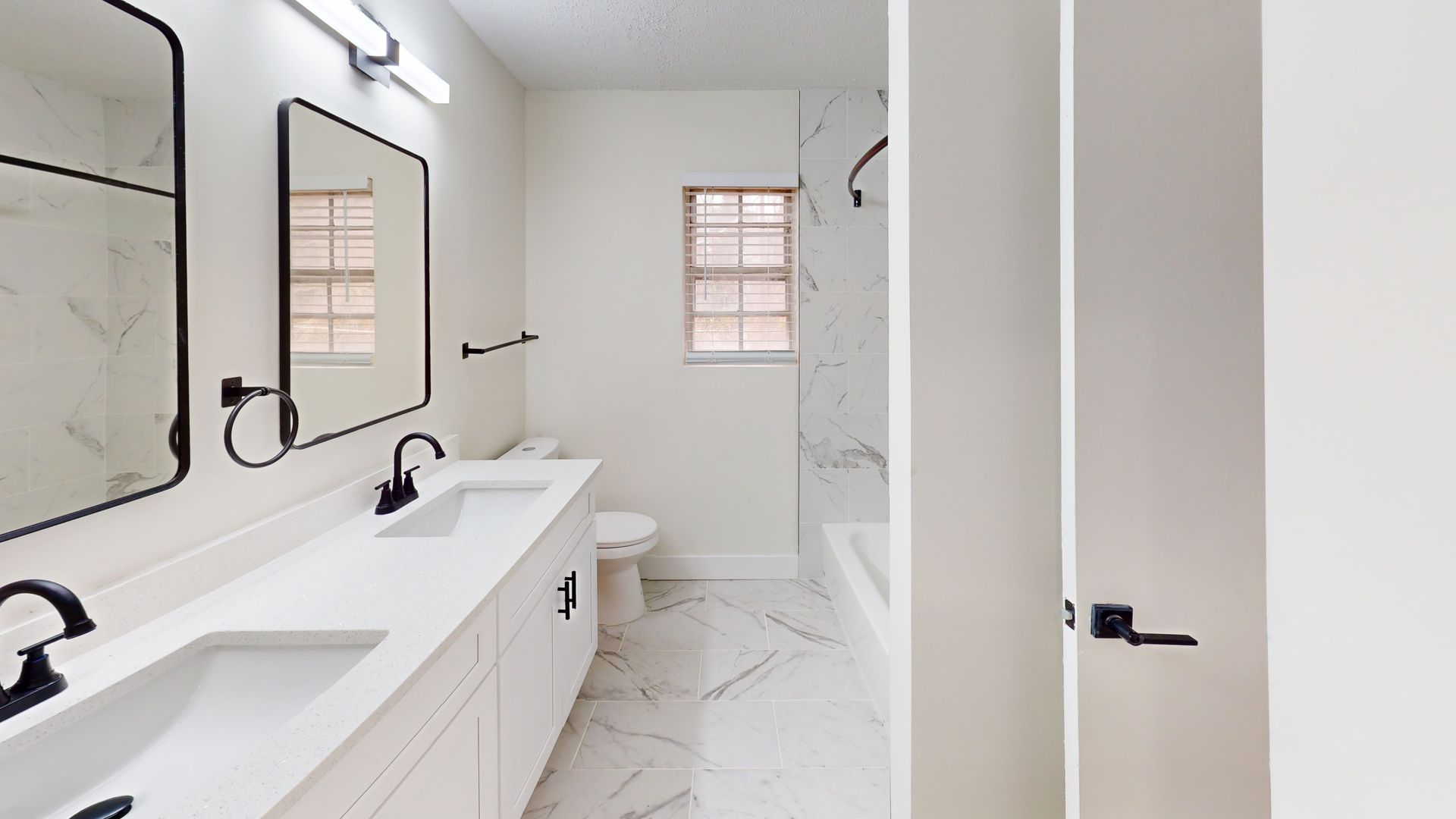 Dining area with glass table, chairs, artwork, and view into kitchen and living room.