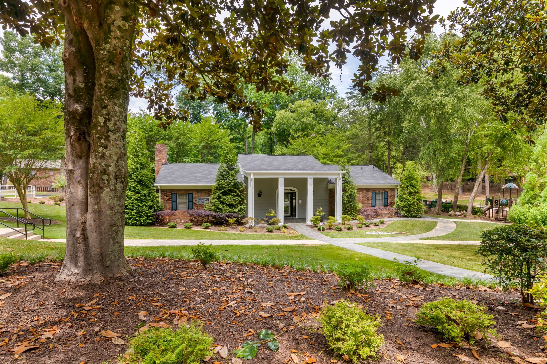 Ranch-style house with brick and gray accents, front porch, and lush landscaping.
