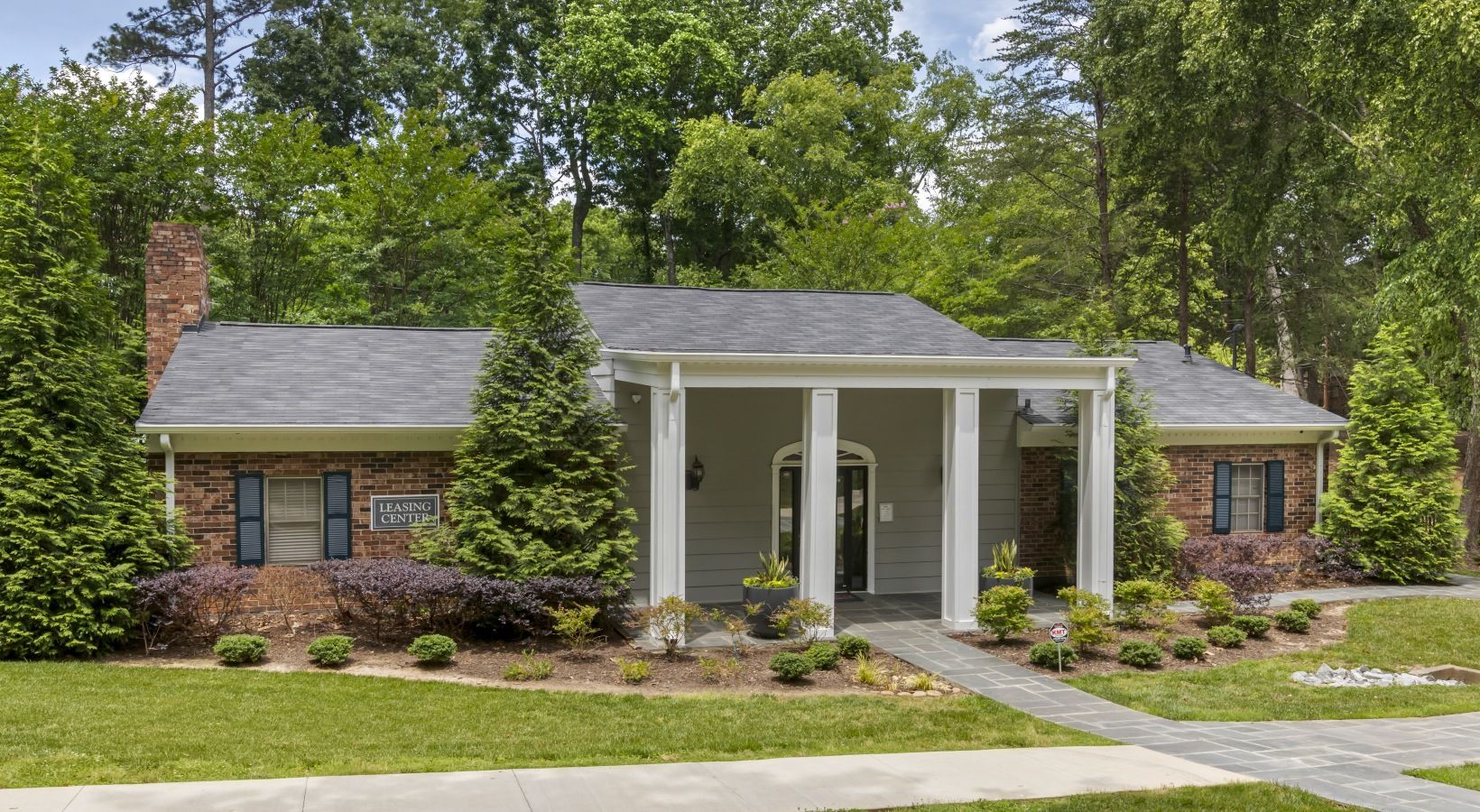 Ranch-style house with brick and gray accents, front porch, and lush landscaping.