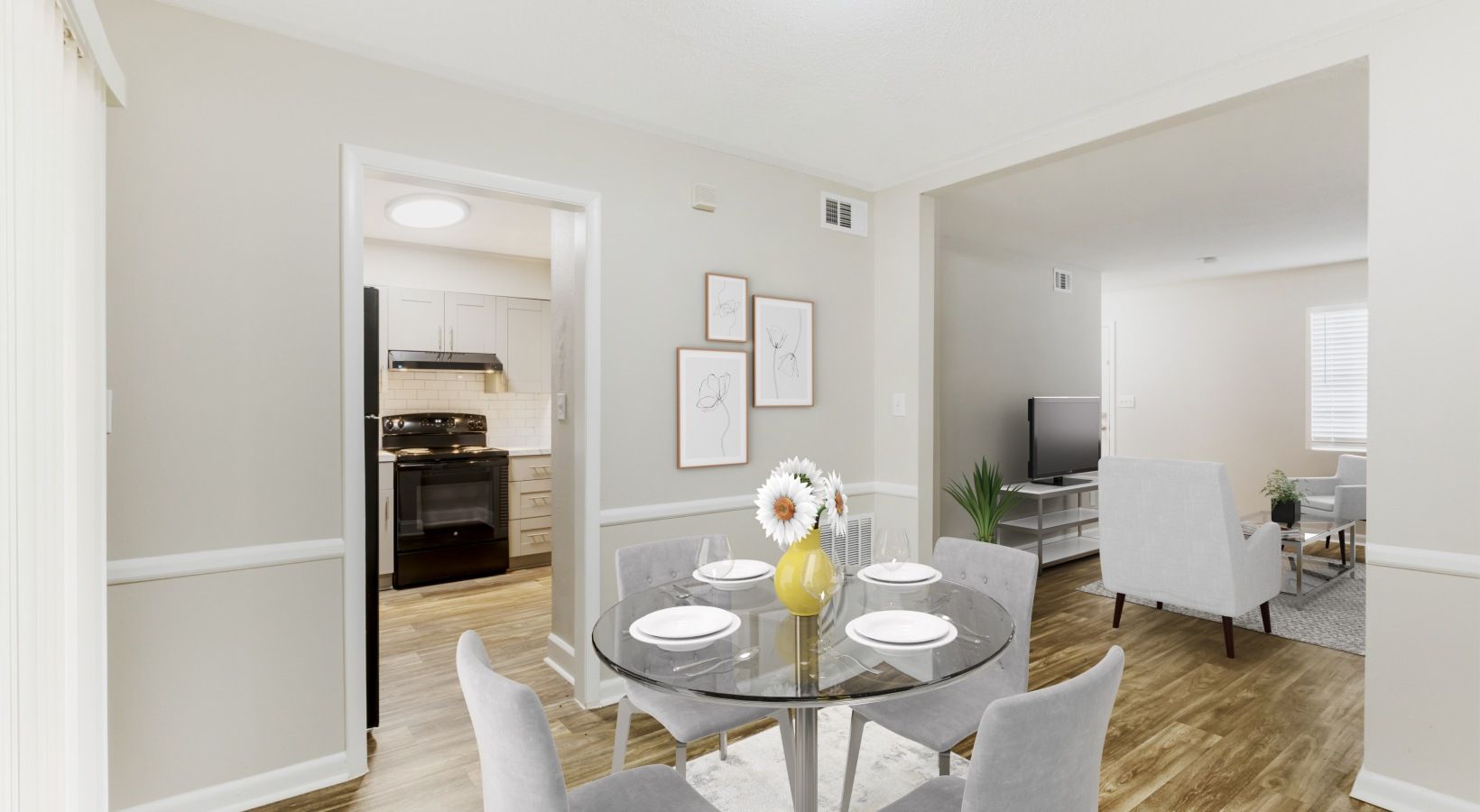 Dining area with glass table, chairs, artwork, and view into kitchen and living room.