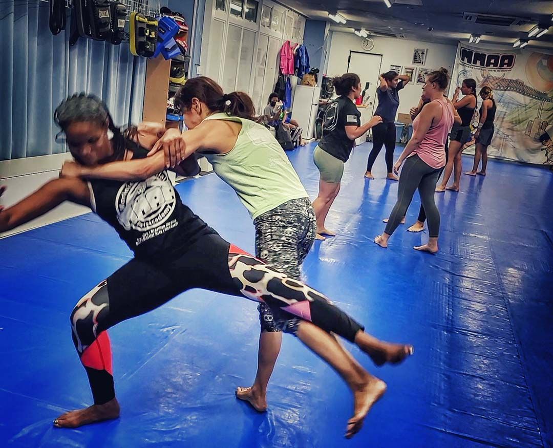 A group of women are practicing martial arts in a gym.