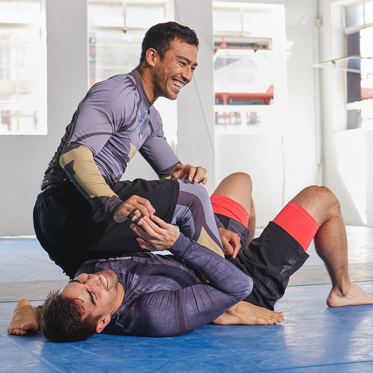 Two men are wrestling on a mat in a gym.